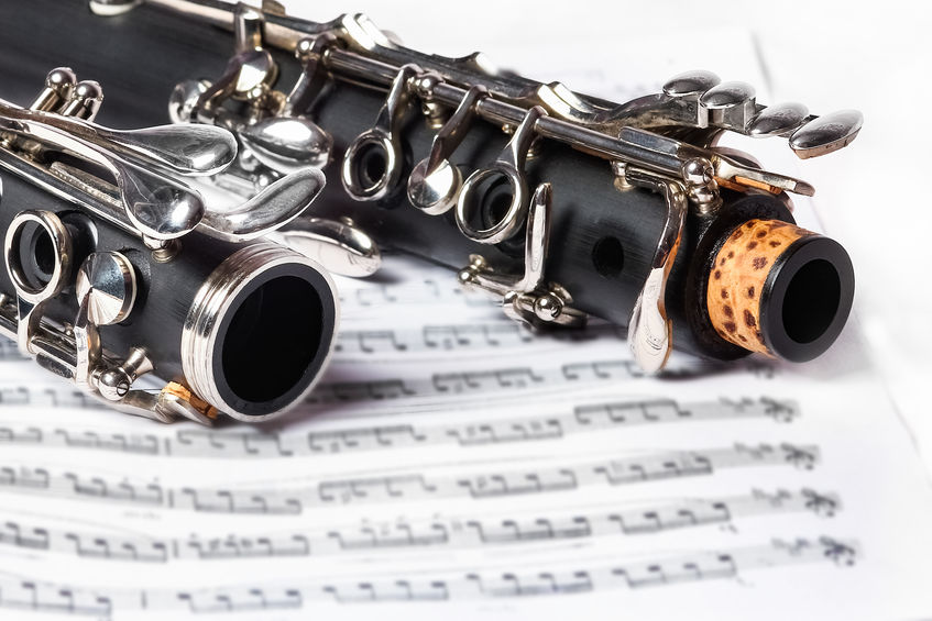 A close-up of a black clarinet with silver keys resting on a sheet of music.